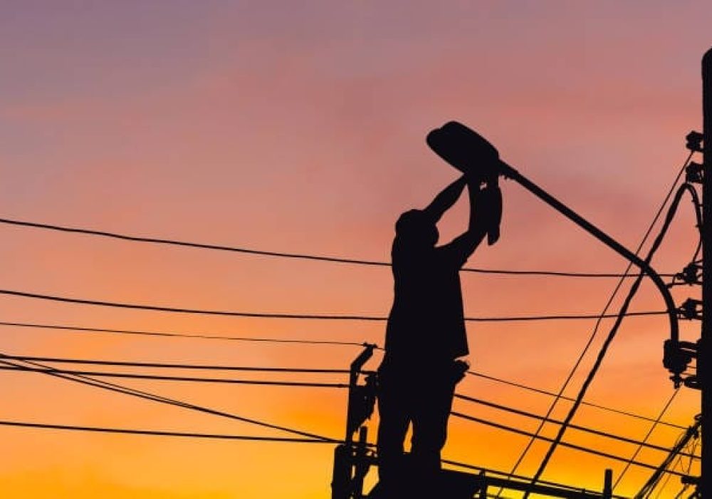 Silueta de electricista comprobando la iluminación del poste de la farola LED, técnico con trayectoria de recorte y conceptos de servicio de mantenimiento